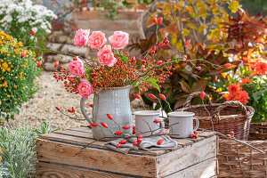 Autumn bouquet of roses and rose hip branches in a jug
