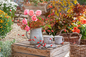 Herbststrauß aus Rosen und Hagebuttenzweigen in Krug