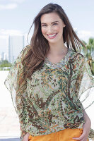 A young woman wearing a colorful, airy summer blouse