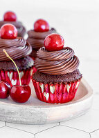 Schokoladen-Cupcakes mit Schokoladenganache und Kirschen