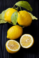 Fresh lemons, whole and halved with leaves