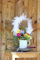 Colorful spring bouquet with feather wreath on wooden chair