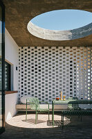 Green outdoor furniture and bench on terrace with decorative concrete blocks and skylight