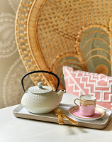 Teapot and porcelain cup, rattan chair in the background