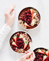 Schokoladen-Porrige-Bowl mit Kirschen, Erdbeeren, Granola und Banane