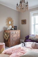 Vintage bedroom with classic chest of drawers and decorative sun mirror