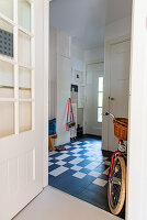 Hallway with chequered tiles and bicycle on the wall