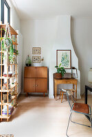 Corner of a living room with retro cupboard, open shelf and houseplants