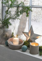 Window sill decorated for Christmas with candles, star and fir branches