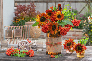 Bouquet on patio table with sunflower 'Velvet Queen', rowan berries, carrot (Ammi majus)