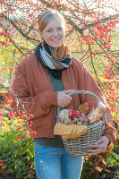 Frau mit Picknickkorb unter Zierapfelbaum im Herbstgarten