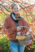 Woman with picnic basket under ornamental apple tree in autumn garden