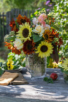 Blumenstrauß mit Sonnenblumen (Helianthus), Rosen (Rosa), Brokkoli, Wilde Möhre, Fuchsschwanz (Amaranthus) auf Gartentisch