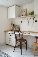 Brightly furnished work area with wall shelf and wooden chair