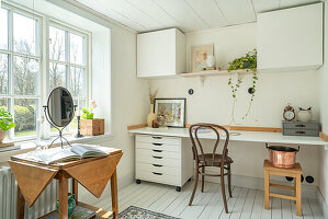 Bright study with white cupboards and wooden furniture