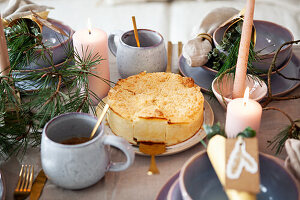 Festively laid table with cake, candles and fir branches