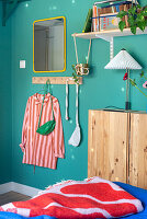 Offenes Regal, darunter schmaler Holzschrank im Schlafzimmer mit blauen Wänden