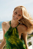 Blonde woman in green halter dress by the sea