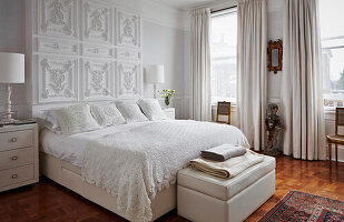 Klassisches Schlafzimmer in Weißtönen und dekorativen Wandelementen