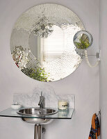 Round mosaic mirror above a modern washbasin in the bathroom