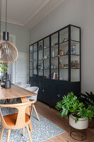 Large metal display cabinet in the dining room with wooden table and modern chairs