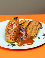 Layered roast (made from vegan meat substitute) with braising sauce and Hasselback sweet potatoes
