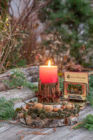 Zimtstangen als Kerzenhalter, Zapfen und Nüsse auf Baumscheibe, Krippenbild, Weihnachtsdekoration auf Gartentisch
