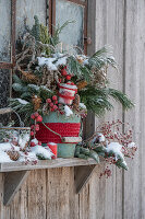 Verschneiter Winterstrauß am Fensterbrett, Kiefernzweige, Goldrute, Blaufichte, Lärche und Zierapfel, mit Schnee im Eimer