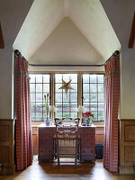 Sprossenfenster mit Stern-Dekoration und Blumenvasen auf Schreibtisch