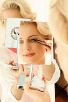 Blonde woman uses eyelash tweezers