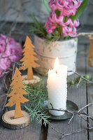 White candle, small DIY Christmas trees, hyacinth (Hyacinthus) in decorative tin on wooden table