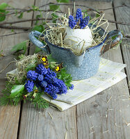 Egg shell filled with grape hyacinths (Muscari) in an enamel pot and bouquet with primrose and grape hyacinths, Easter decoration