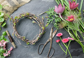 Kranz binden aus Küchenschelle (Pulsatilla), Vergissmeinnicht, Gänseblümchen (Bellis) und Birkenzweigen