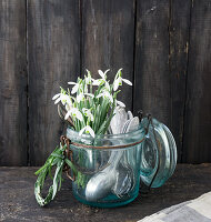 Strauß aus Schneeglöckchen (Galanthus) und altes Besteck im Bügelglas