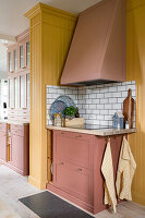 Kitchen with terracotta-colored cupboards, yellow wall paneling and tiled backsplash