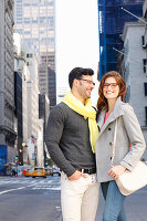 A couple stands on the street with skyscrapers