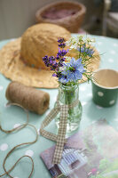 Sommerliche Tischdeko mit Lavendel und Strohhut auf gepunkteter Tischdecke