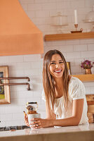 Smiling woman holding mug in kitchen\n