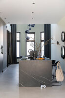 Open-plan kitchen with dark marble island and black curtains