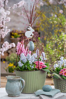 Hyazinthen (Hyacinthus), Kegelblume (Puschkinia), und Primeln (Primula) in Töpfen mit Ostereiern auf der Terrasse