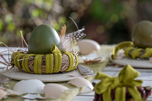 Osterei im Nest mit Federn und Eierschalen dekoriert auf Gartentisch