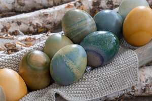 Easter eggs colored with natural dyes on knitted cloth on birch branches