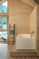 Modern bathroom with free-standing, angular bathtub and Alpine-style wood paneling