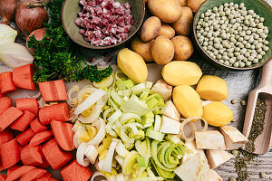Zutaten für deftigen Erbseneintopf - Speck, Möhren, Porree, Kartoffeln, Zwiebeln, Majoran