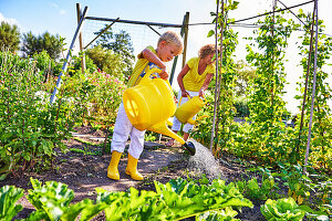 Boy and mother watering vegetable beds