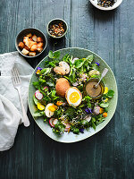Colourful wild herb salad with petals and fried egg