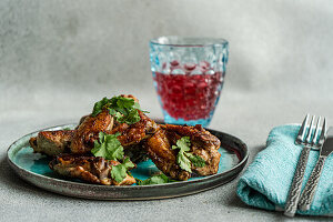 Roasted chicken wings with coriander and a glass of cherry cocktail