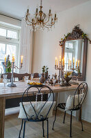 Dining area with wooden table, candlesticks, chandelier and antique mirror