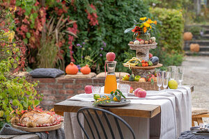 Erntedank-Etagere auf gedeckter Tafel im herbstliche Garten