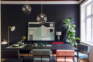 Dining room with modern chairs, dark table and geometric artwork on black wall